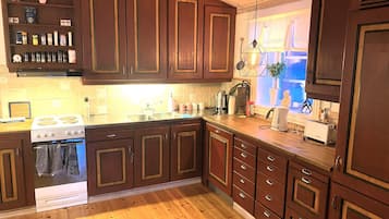 A kitchen with wooden cabinets, a stove, a sink, and a window with a view.