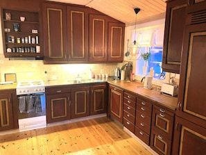 A kitchen with wooden cabinets, a stove, and a window with a view. - 5 Person Holiday Home in Idre (Idre)