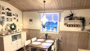 A dining area with a wooden table, white chairs, and a window with a view. - 5 Person Holiday Home in Idre (Idre)