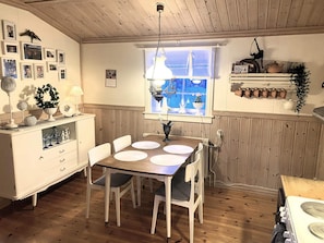 A dining area with a wooden table, white chairs, and a window with a view. - 5 Person Holiday Home in Idre (Idre)