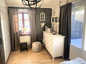 A bedroom with a dresser, a small stool, a window with curtains, a radiator, and a ceiling light fixture. - 5 Person Holiday Home in Idre (Idre)