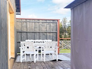 A wooden deck with a white outdoor seating area and a grey building in the background. - 5 Person Holiday Home in Idre (Idre)