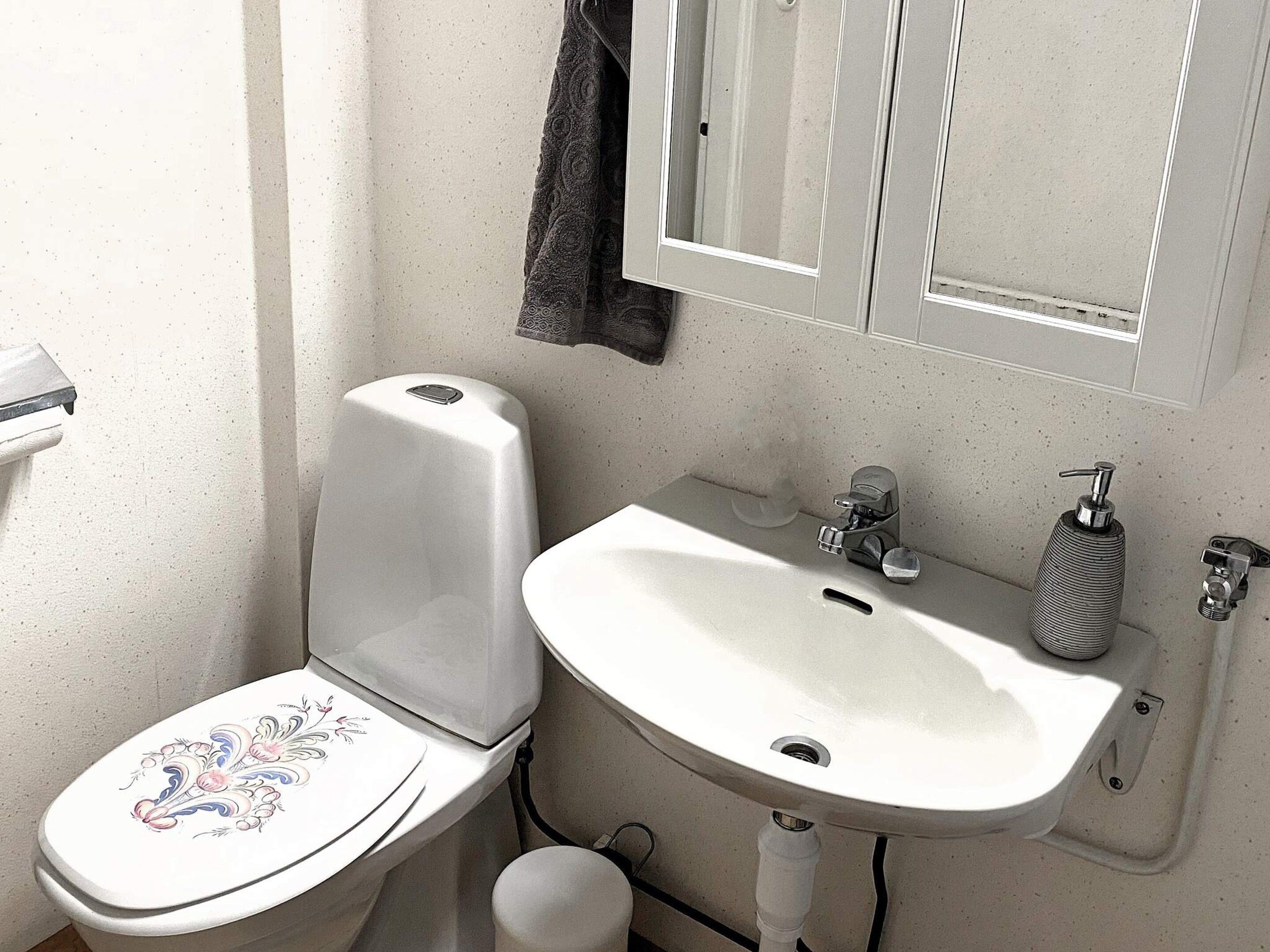 A bathroom with a toilet, sink, and mirror.