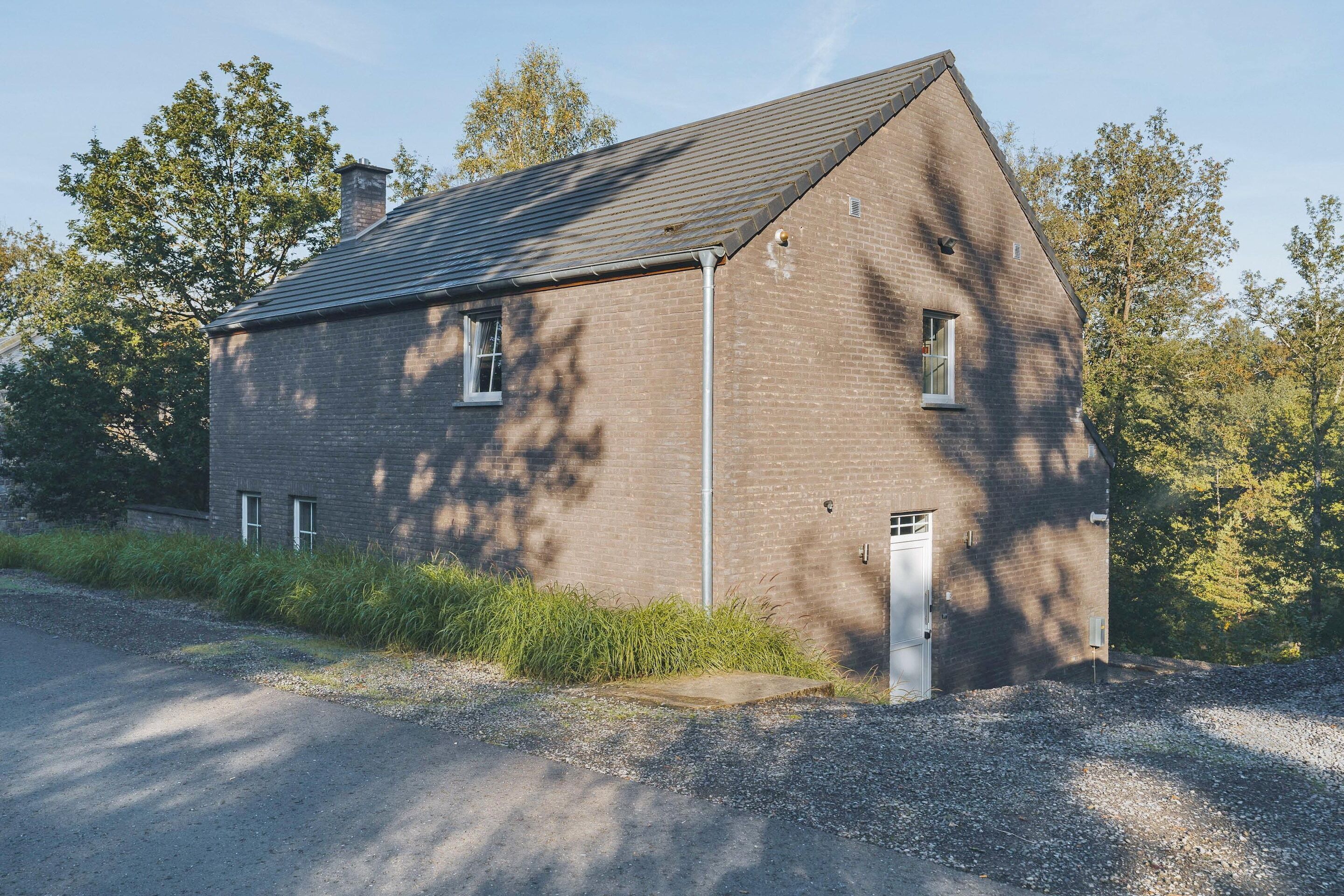 A single-story brick building with a sloped roof, a small window, and a door.