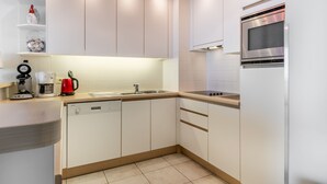 Eine moderne Küche mit weißen Schränken, einem Edelstahlkühlschrank, einer Kaffeemaschine und einem Geschirrspüler.