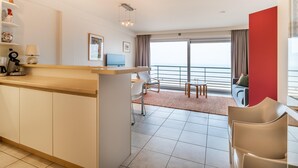Ein modernes Hotelzimmer mit Küchenbereich, einem Esstisch und einem Balkon mit Blick.