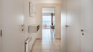 Ein Flur mit Heizkörper, Wand-Fernseher und einer Tür zu einem Balkon mit Blick.
