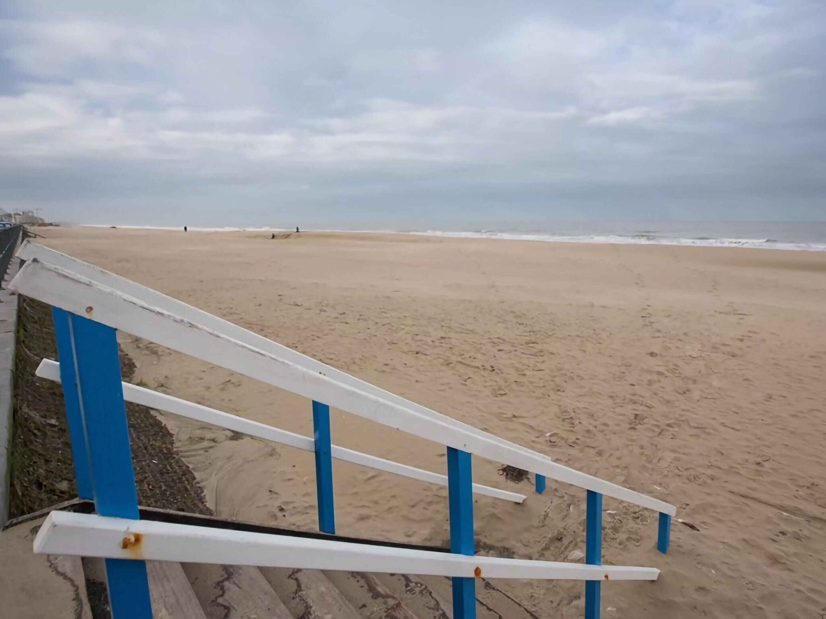 A beach with a white and blue railing.