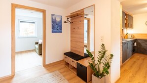 A modern apartment with a wooden floor, a built-in bench, a mirror, a potted plant, and a kitchen area. - Apartment in Uderns Near Spieljoch Ski (Uderns)
