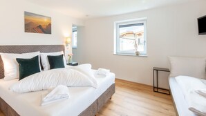 A modern hotel room with a large bed, a smaller bed, a window with a view, and a flat-screen TV. - Apartment in Uderns Near Spieljoch Ski (Uderns)