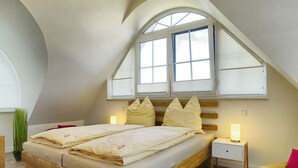Ein Schlafzimmer mit einem hölzernen Bett, zwei Nachttischen mit Lampen, einem Fenster mit Jalousien und einer gewölbten Decke.