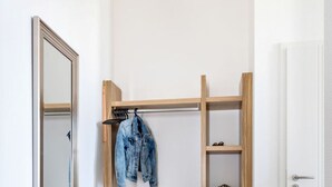 Um quarto pequeno e luminoso, com uma estante de madeira e um espelho.
