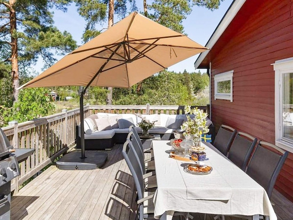 A wooden deck with a table set for dining, outdoor seating, and a barbecue grill. - 6 Person Holiday Home in Mariefred-by Traum (Mariefred)