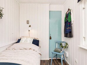 A bedroom with a bed, a chair, a door, and a wall-mounted coat rack. - 6 Person Holiday Home in Mariefred-by Traum (Mariefred)