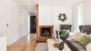A living room with a fireplace, a sofa, a coffee table, and a door leading to another room. - 6 Person Holiday Home in Mariefred-by Traum (Mariefred)