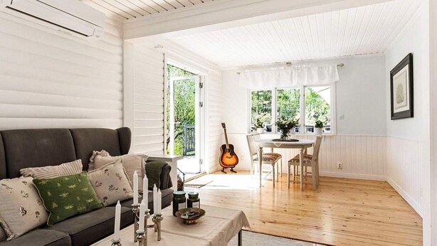 A cozy living room with a dark sofa, a table with candles, and a guitar. - 6 Person Holiday Home in Mariefred-by Traum (Mariefred)