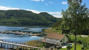 En fastighet vid sjön med en brygga, ett litet hus och en gräsyta.