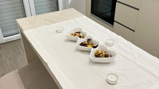 A kitchen counter with three white bowls containing dried fruits and nuts, and two small white candles. - Apartments Jelena - One Bedroom Apartment (Dubrovnik)