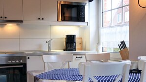 A modern kitchen with white cabinetry, a Bosch oven, a microwave, a coffee maker, and a window with a view of buildings. - Overt Meer 6 Modern Retreat (Grosefehn)