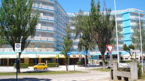 Un hotel de varios pisos con balcones, un paso de peatones y un cartel de no estacionamiento.