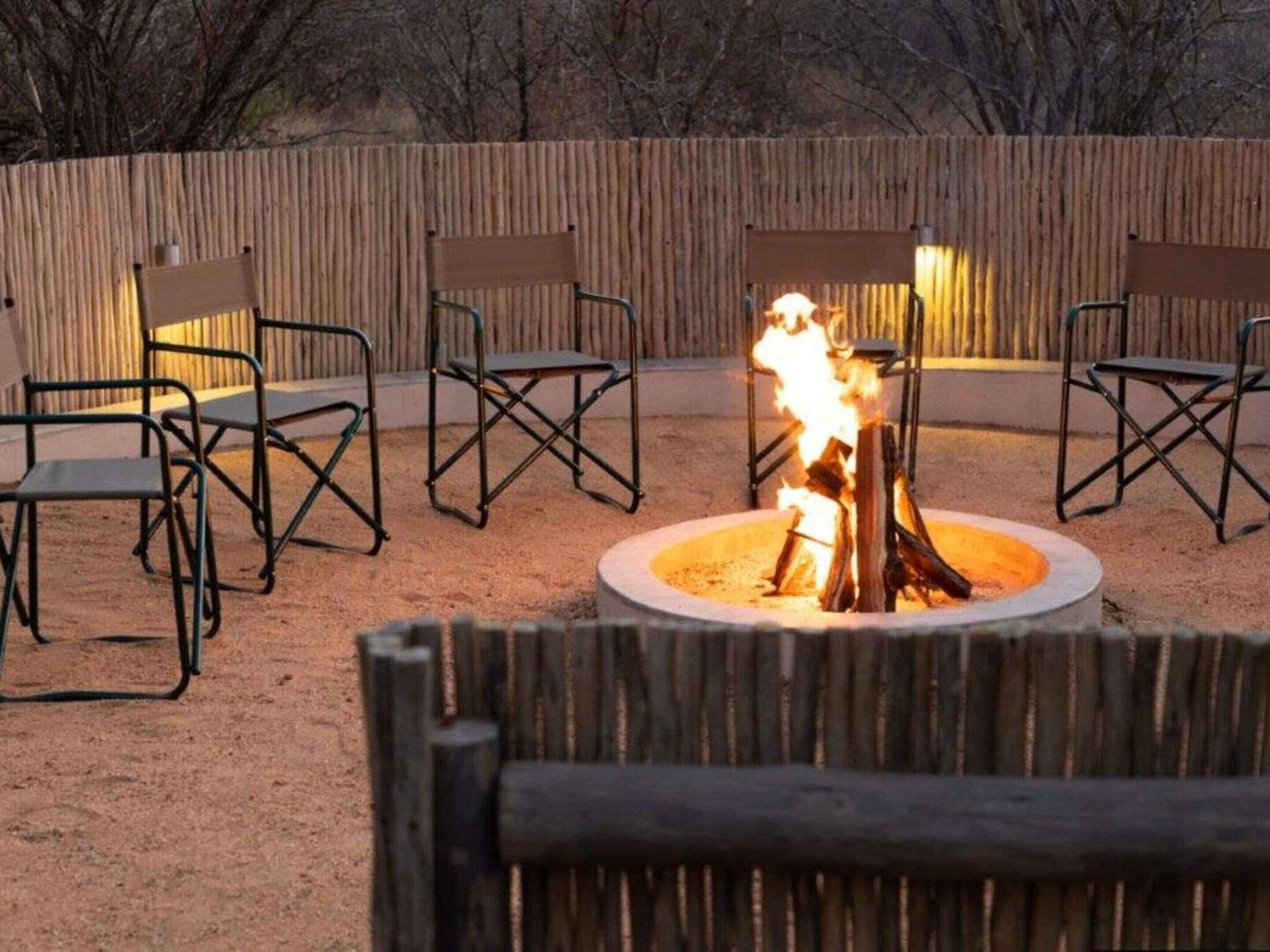 An outdoor seating area with a fire pit in the center surrounded by chairs.