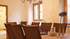 A dining area with wicker chairs, a wooden table, and a chandelier. - Voor 8 tot 12 Personen (Neumagen-Dhron)