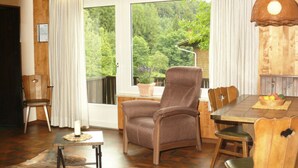 A cozy room with a large window, wooden furniture, and a rustic rug.