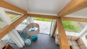 A modern interior with a glass ceiling, a hanging light fixture, a sofa, and a dining area. - Holiday Home in Renesse Near the Beach (Renesse)