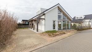 A modern two-story house with a sloped roof, large windows, and a paved driveway. - Holiday Home in Renesse Near the Beach (Renesse)