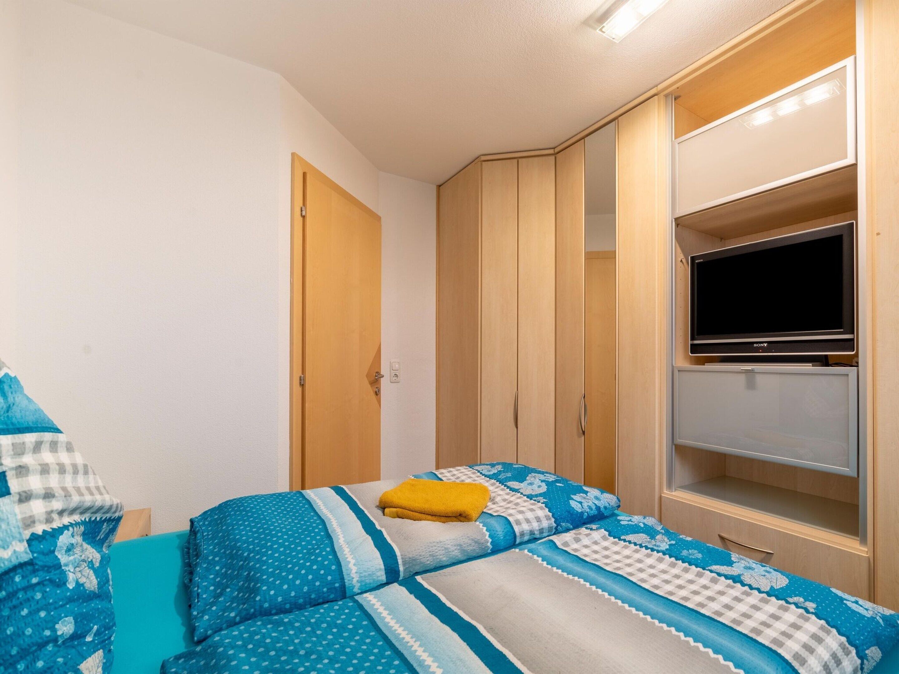 A bedroom with a bed, a wardrobe, and a television.