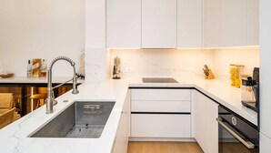 A modern kitchen with white cabinetry, a stainless steel sink, and a built-in oven. - Apartment Villa Claudia (Dubrovnik)