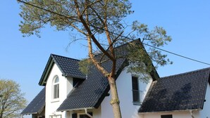A two-story house with a sloped roof, white exterior walls, and green shutters. - Holiday Home Water View (Rankwitz)