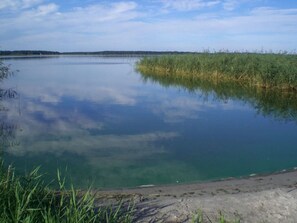 A calm lake with clear water reflecting the sky and surrounding vegetation. - Holiday Home Water View (Rankwitz)