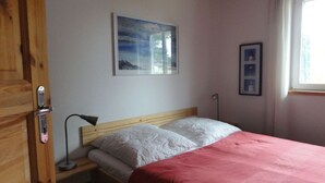 A bedroom with a bed, a nightstand, a lamp, and a window. - Holiday Home Water View (Rankwitz)