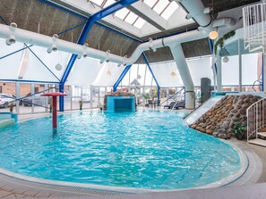 An indoor swimming pool with a slide, blue structural beams, and a view of the outside. - 4 Person Holiday Park Home in Hejls (Hejls)