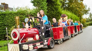 A miniature train with passengers and a mascot.