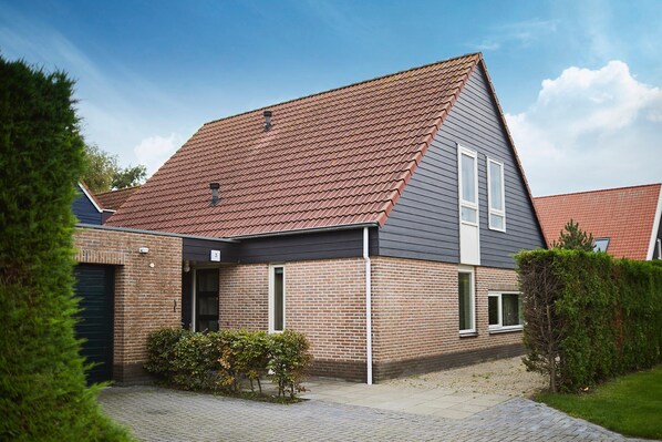 A modern two-story house with a sloped roof, brick exterior, and a paved driveway. - Group Accommodation in Zeeland With Garden (Heinkenszand)