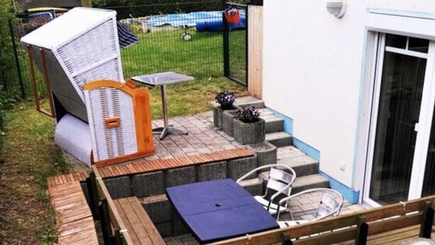 Un espace extérieur aménagé avec une terrasse en bois, une table et une chaise.