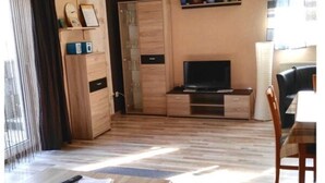Un salon moderne doté d’un téléviseur à écran plat, de meubles en bois et d’un coin repas avec une table et des chaises.