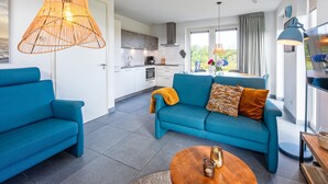 Ein modernes Wohnzimmer mit Sofa, Couchtisch und Essbereich mit Tisch und Stühlen.