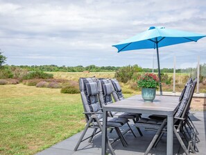 Un patio al aire libre con una mesa, sillas, un paraguas azul y una planta en maceta.