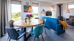 Ein modernes Wohnzimmer mit einem runden Holztisch, einem blauen Sofa und einem Fernseher.