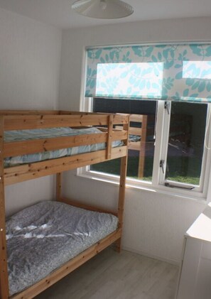 A bunk bed room with a window and a white cabinet.