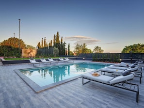 A swimming pool with lounge chairs and a clear sky.