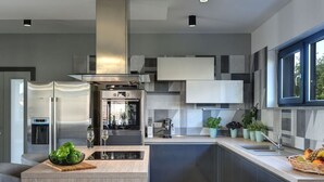 Een moderne keuken met een centraal eiland, inbouwapparatuur en een groot raam voor natuurlijk licht.