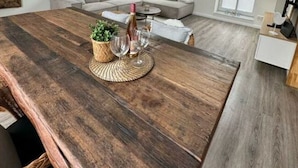 A spacious loft with exposed wooden beams, a large wooden dining table, and a cozy seating area with a sofa and a small coffee table. - Fischerstuv Modern Retreat (Toenning)