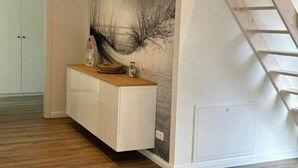 A modern interior with a wooden floor, a white cabinet, and a staircase. - Fischerstuv Modern Retreat (Toenning)
