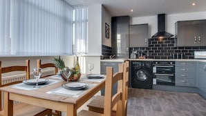 Une cuisine moderne avec des meubles gris, une hotte noire et un lave-linge encastré.