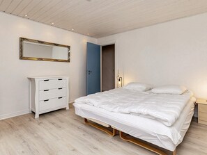 A bedroom with a bed, a dresser, a mirror, and a door. - 6 Person Holiday Home in Albaek (Aalbaek)