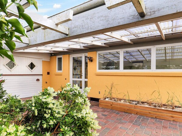 A residential property with a covered patio, a yellow exterior wall, a white garage door, and a window with a view of the sky.